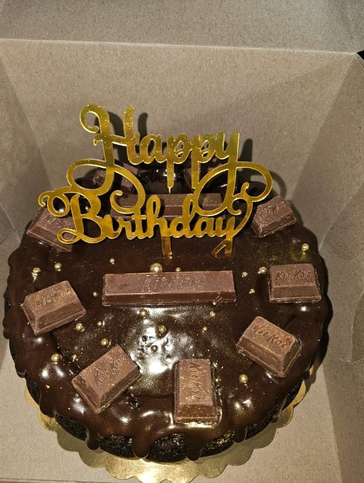 Chocolate ganache cake topped with Kit Kat pieces and gold pearls.