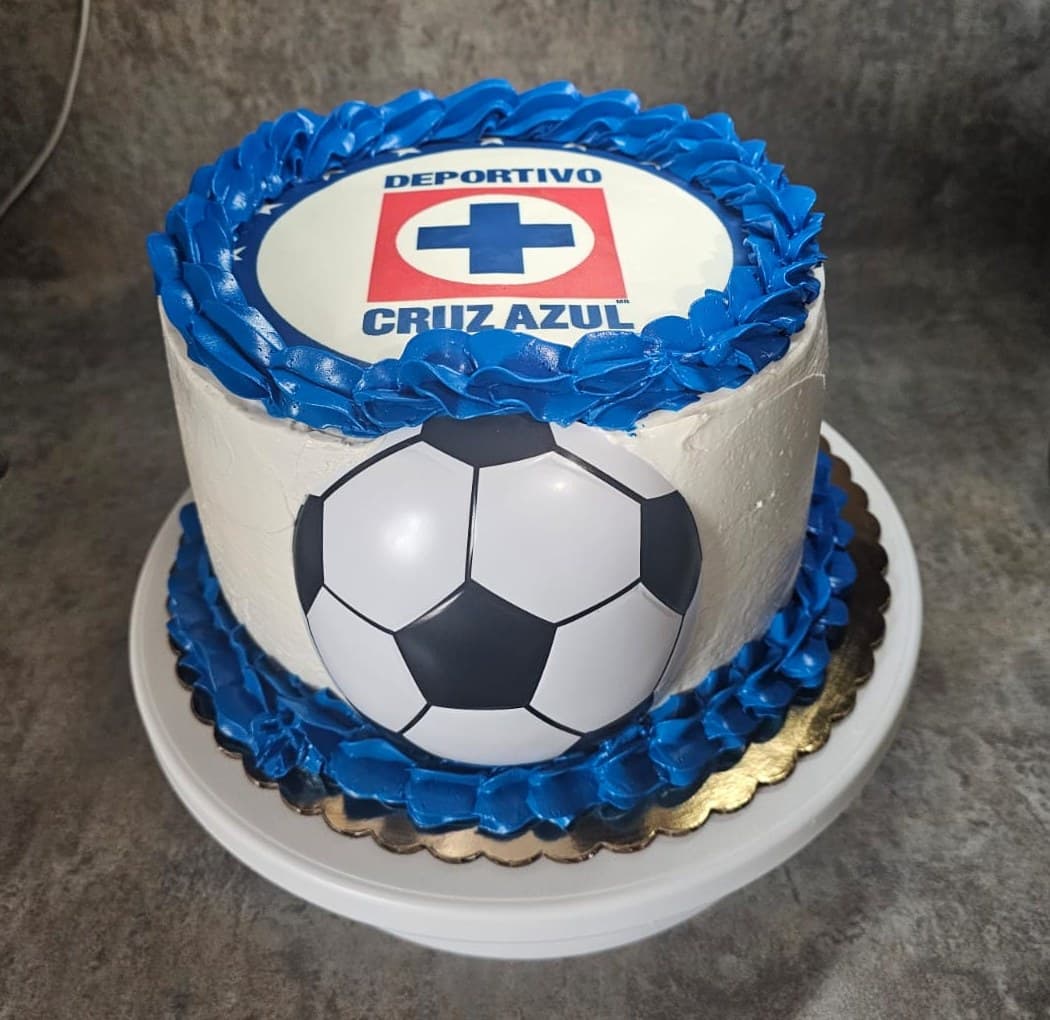 White cake with blue piping, a Cruz Azul crest and a soccer ball.