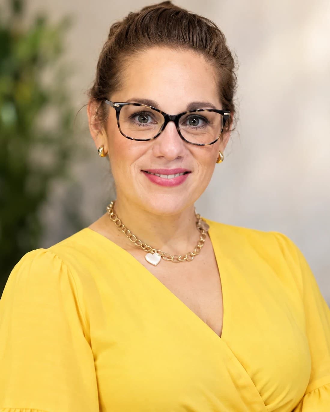 Crystal Gallegos, the baker behind Heavenly Bites by Crystal, smiling in a yellow blouse and tortoiseshell glasses.